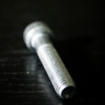 Stainless steel threaded rod on black reflective surface