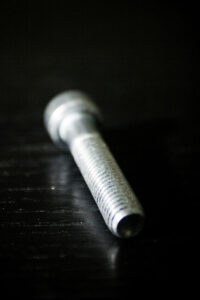 Stainless steel threaded rod on black reflective surface